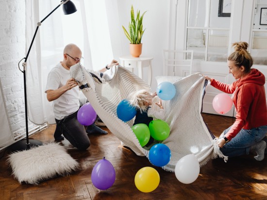 Rodzice szykują z dzieckiem dom na jego urodziny i podrzucają balony.