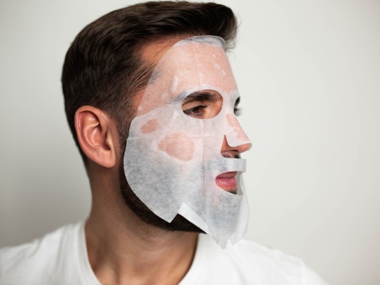 Mężczyzna z brodą ma nałożona na twarz maseczkę w płachcie