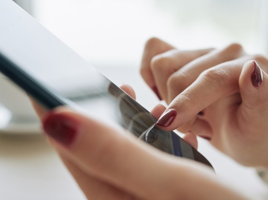 Kobiece dłonie wyszukują na telefonie aplikacji, która będzie pomocna w zorganizowaniu sprzątania.