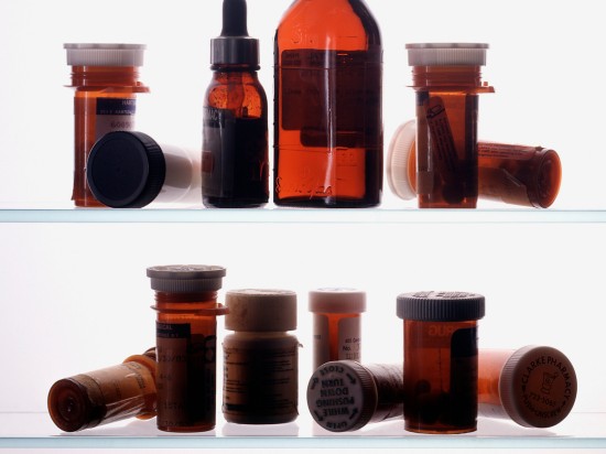 Różnego rodzaju leki rozstawione na półkach obrazują domową apteczkę.