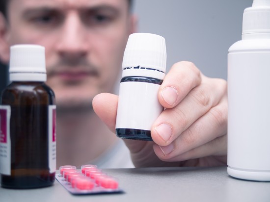 Mężczyzna układa różne leki w swojej domowej apteczce.