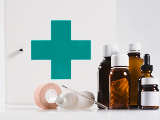 Przykład domowej apteczki, która zawiera syropy, bandaże oraz różne tabletki.