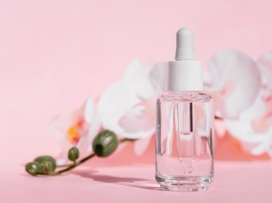 Serum do twarzy z zawartością kwasów PHA na różowym tle z kwiatem.