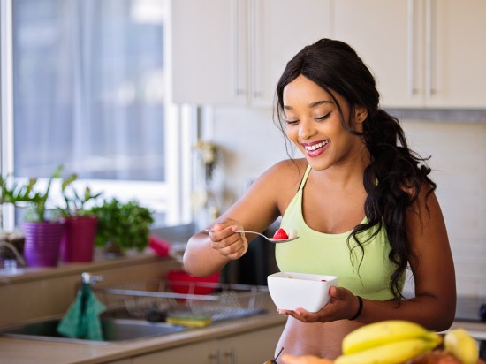 Kobieta po treningu je przekąskę, która składa się z różnych owoców.