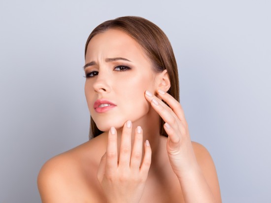 Kobieta ze skórą suchą pokazuje podrażniony policzek