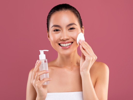 Kobieta oczyszcza skórę przy pomocy olejku oraz wacika