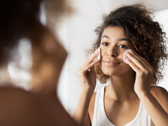 Kobieta oczyszcza skórę przy pomocy dwóch wacików do twarzy