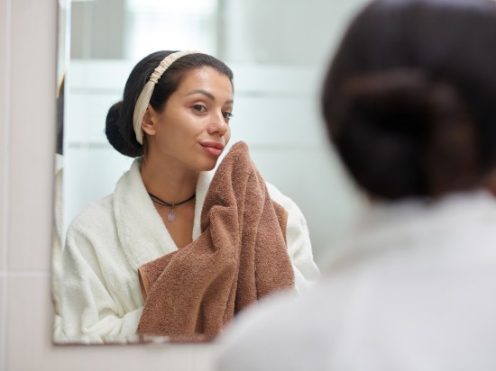 Kobieta wyciera ręcznikiem twarz po umyciu.