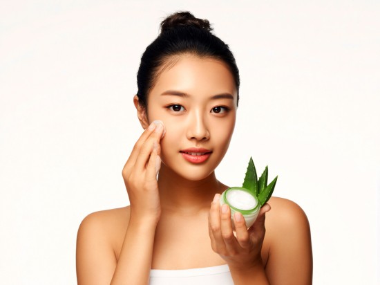 Kobieta smaruje skórę twarzy kremem z aloesu.