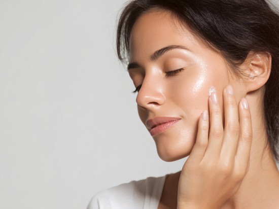 Kobieta z cerą dojrzałą smaruje kremem policzek.