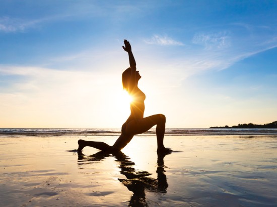 Kobieta ćwiczy jogę o wschodzie słońca utrzymując zdrowy tryb życia