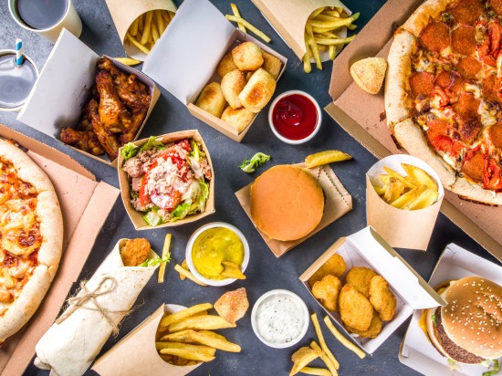 Fast food na stole – pizza, burger, frytki i nuggetsy.