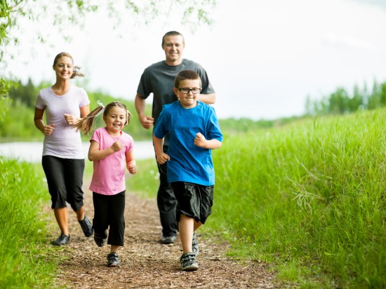 Mama, tata i dwójka dzieci uprawiają razem sport biegając w lesie. Tym samym budują wspólnie zdrowe nawyki w rodzinie.