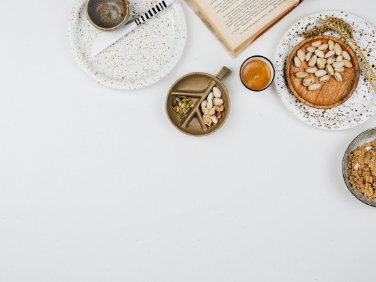 Zdrowe przekąski typu pistacje, orzeszki na białym tle. Obok lezy książka.