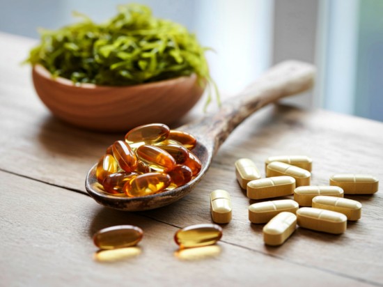 Koło miski z rukolą leży łyżka z suplementami.