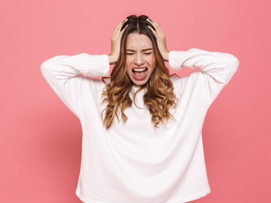 Kobieta trzymająca się za głowę, wyrażająca silny stres i napięcie.