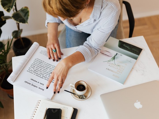 Kobieta pracuje zdalnie z domu przy filiżance kawy.