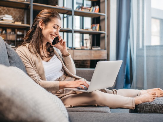 Uśmiechnięta kobieta pracuje zdalnie z domu.
