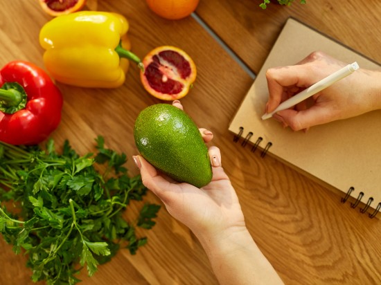 Kobieta zapisuje tygodniowy jadłospis oparty o zdrowe produkty.