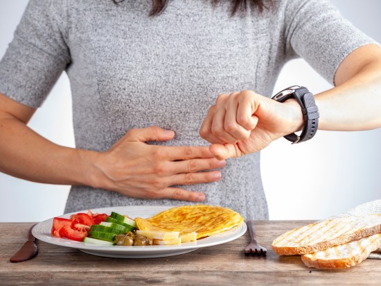 Kobieta patrzy na zegarek, bo kończy się czas bez posiłku w poście przerywanym.