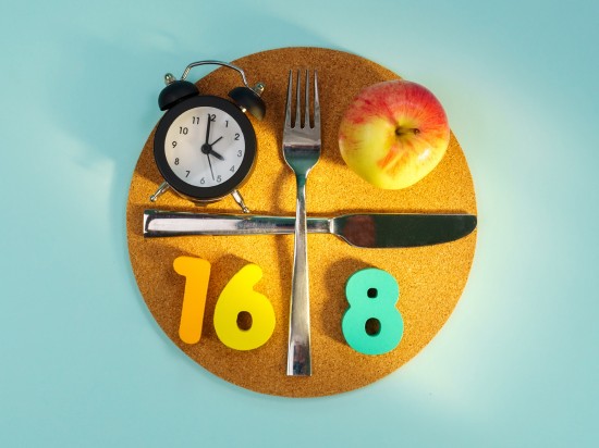 Jabłko, zegarek, sztućce oraz cyfry razem obrazują post przerywany w formule 16 na 8.