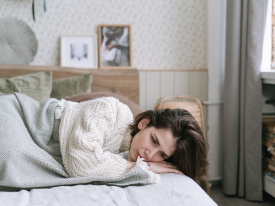 Kobieta próbuje uspokoić myśli przed zaśnięciem w łóżku.