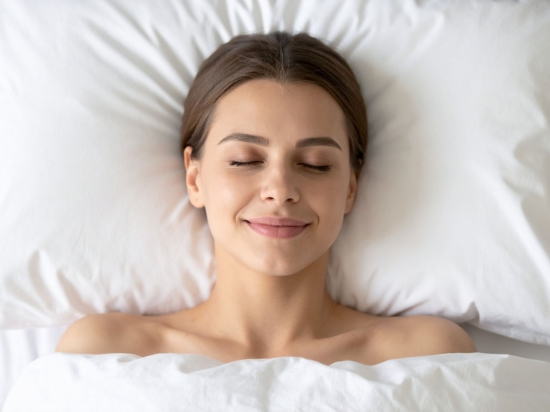 Kobieta leży w łóżku uśmiechnięta wypoczywając.
