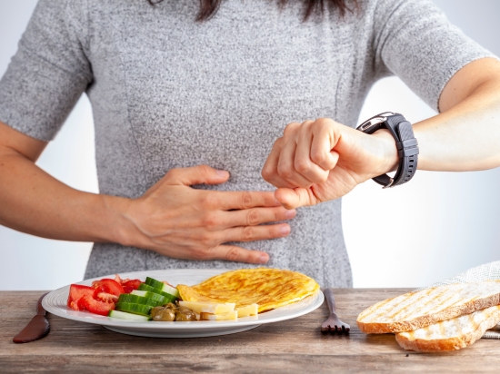 Kobieta patrzy na zegarek, ponieważ stosuje post przerywany i nie wie czy już jest okno żywieniowe.